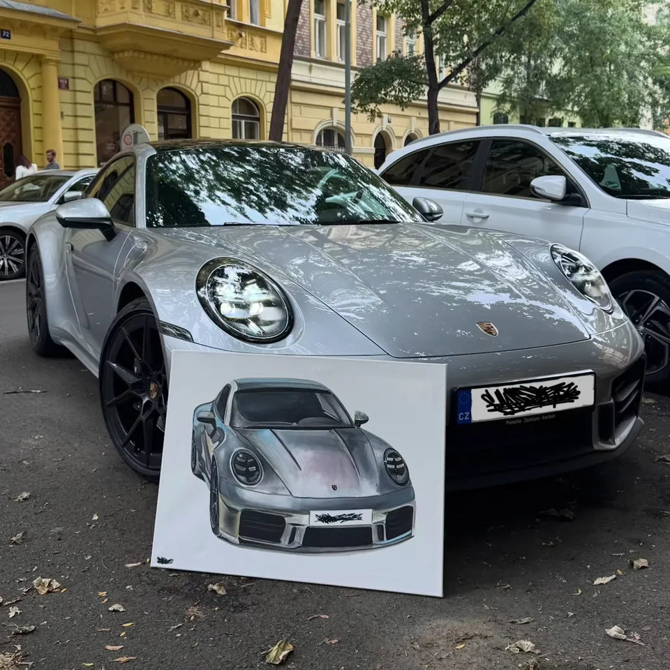 Obraz stříbrného Porsche 911 opřený o přední nárazník skutečného vozu v ulici